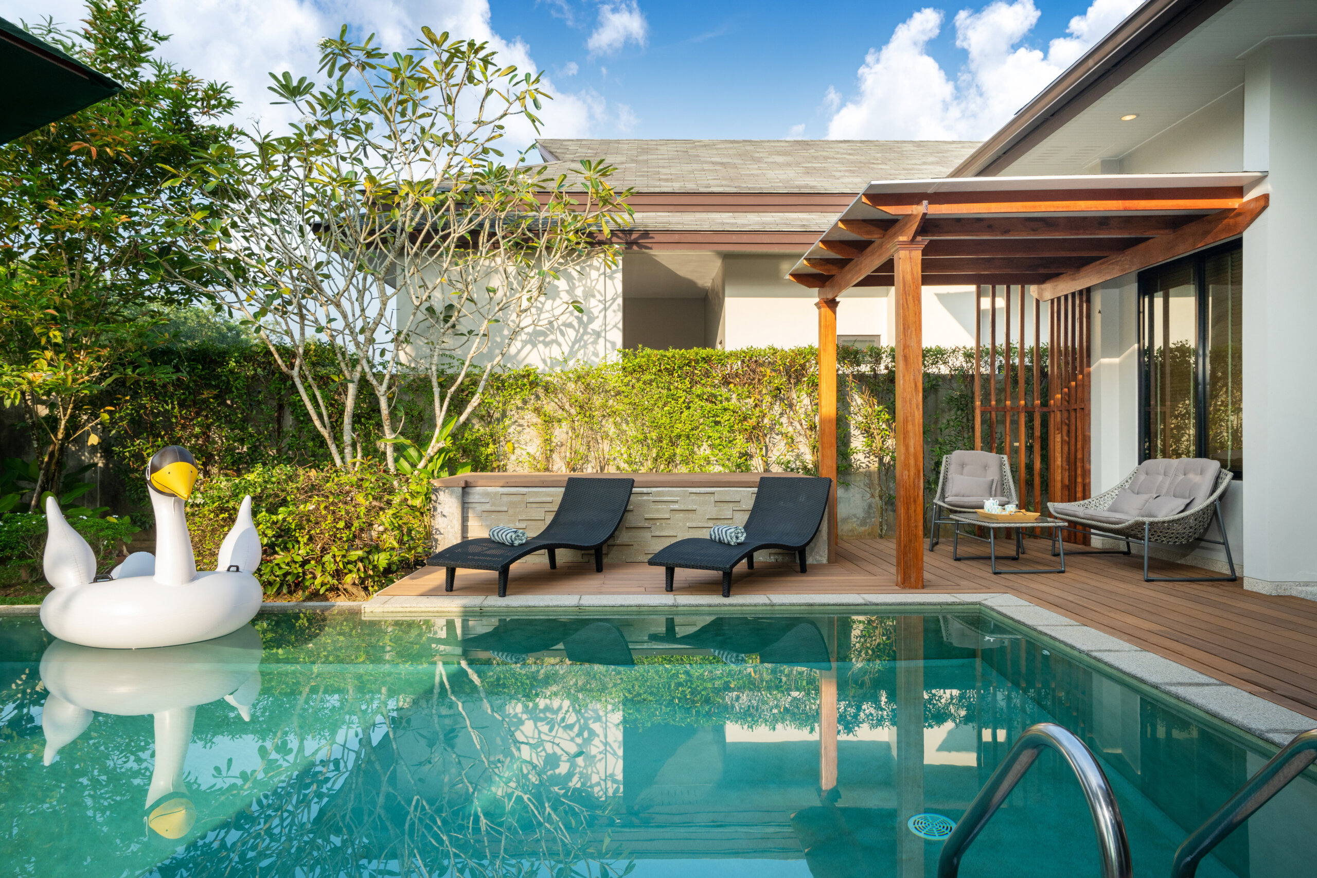 A turquoise and Blueish pool in a backyard patio.