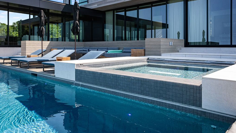 Sleek inground pool with spa feature near a contemporary house, demonstrating clear water with proper filtration.