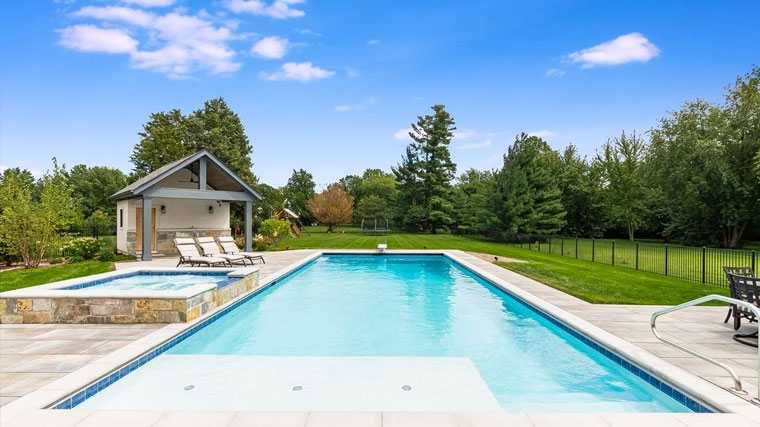 amily-friendly rectangular pool with perimeter fencing and pool house in a secure backyard