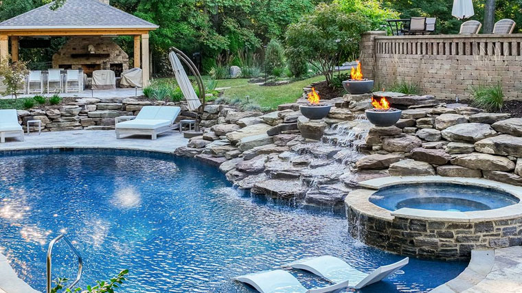 Heated outdoor pool featuring natural stone design with fire features for year-round enjoyment